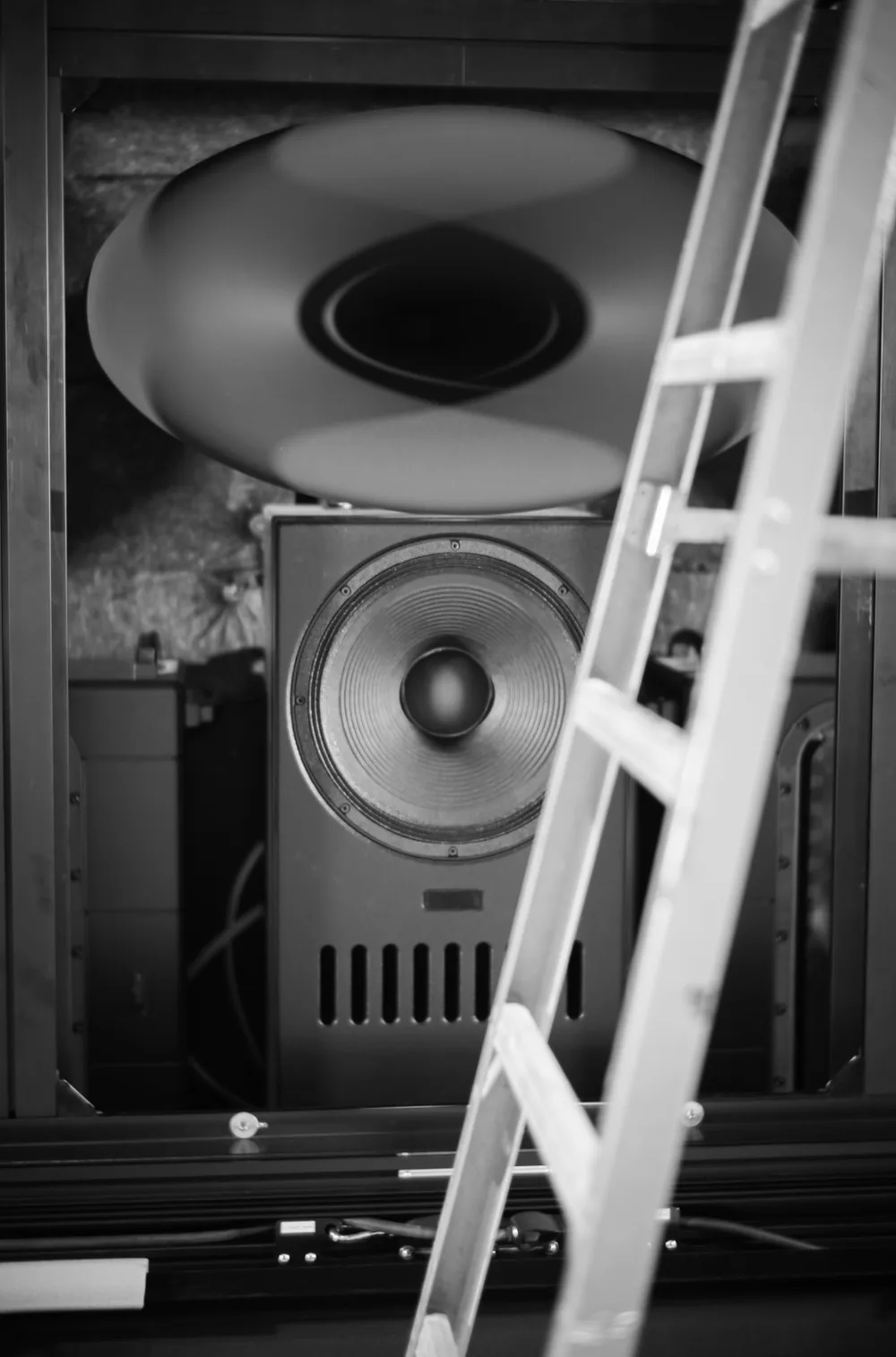 An Ascendo Black Swan loudspeaker with its large horn, seen past a stepladder during installation