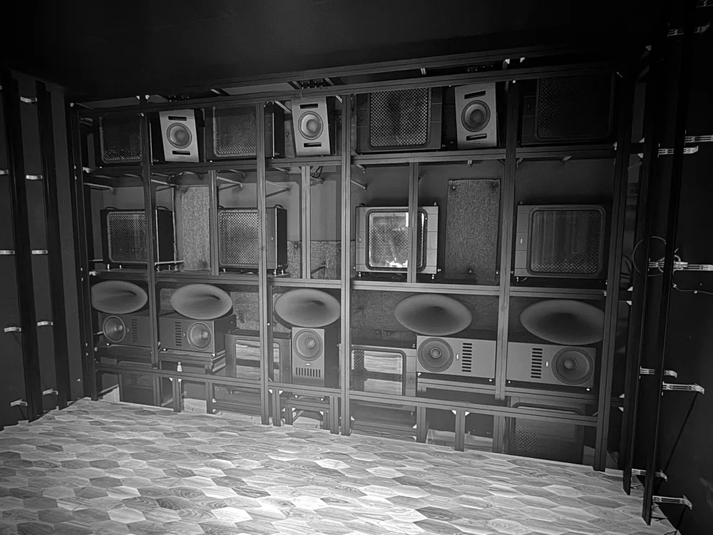 The front wall before the screen was fitted, showing five horn-loaded front loudspeakers and an array of square subwoofers on an aluminium frame, with three height channels hung above