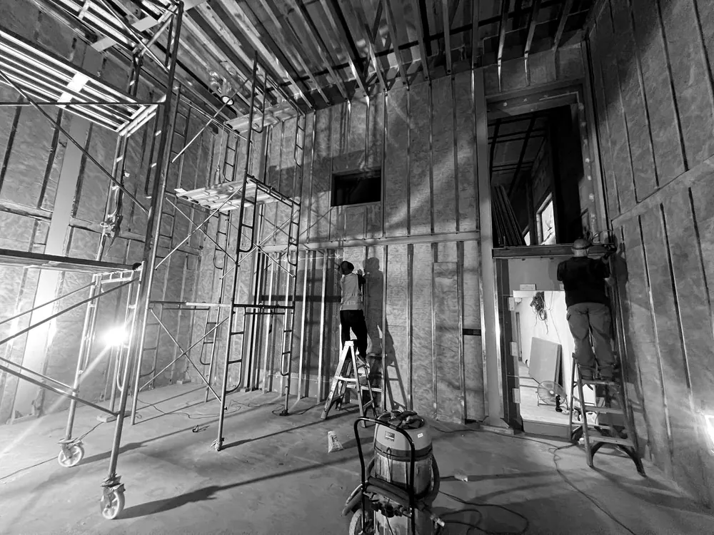 Installers on ladders fitting insulation into the steel-framed walls of the inner room