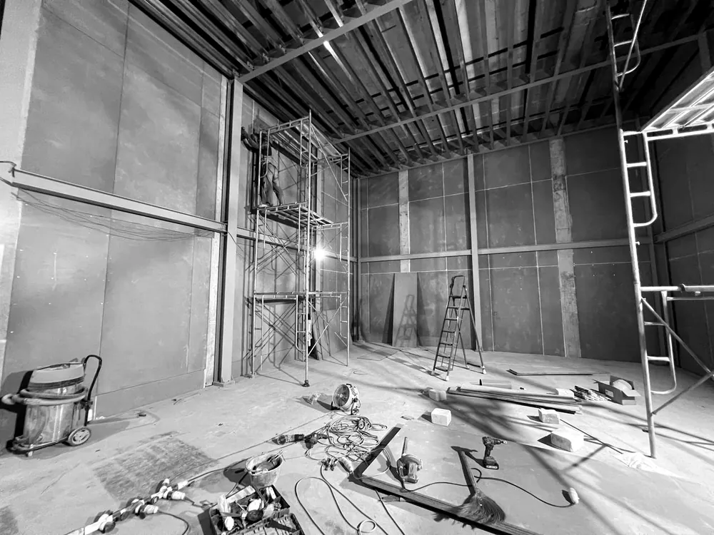 Two installers walking through the steel frame of the inner room, with the steel ceiling structure overhead