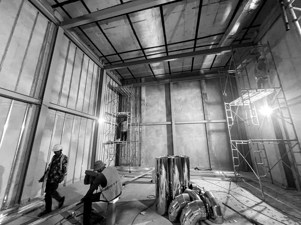The steel frame of the inner room with scaffolding against the walls and tools on the floor