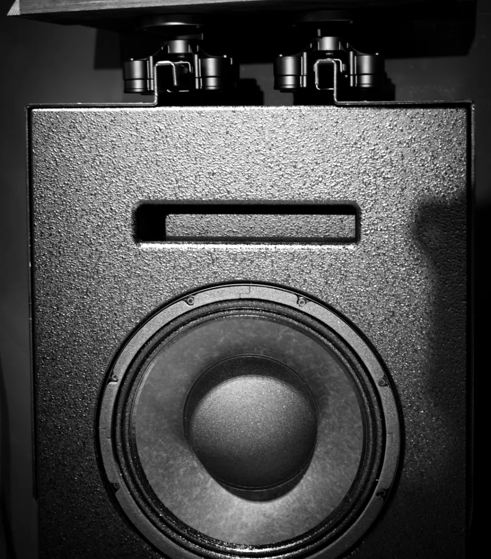An Ascendo Pro 12 surround loudspeaker with two IsoAcoustics V120 isolators above it on the bespoke mount