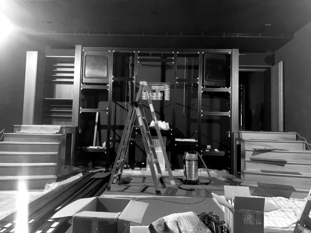 The rear wall of the cinema during assembly on site, with timber stair units and a ladder in front of the wall frame
