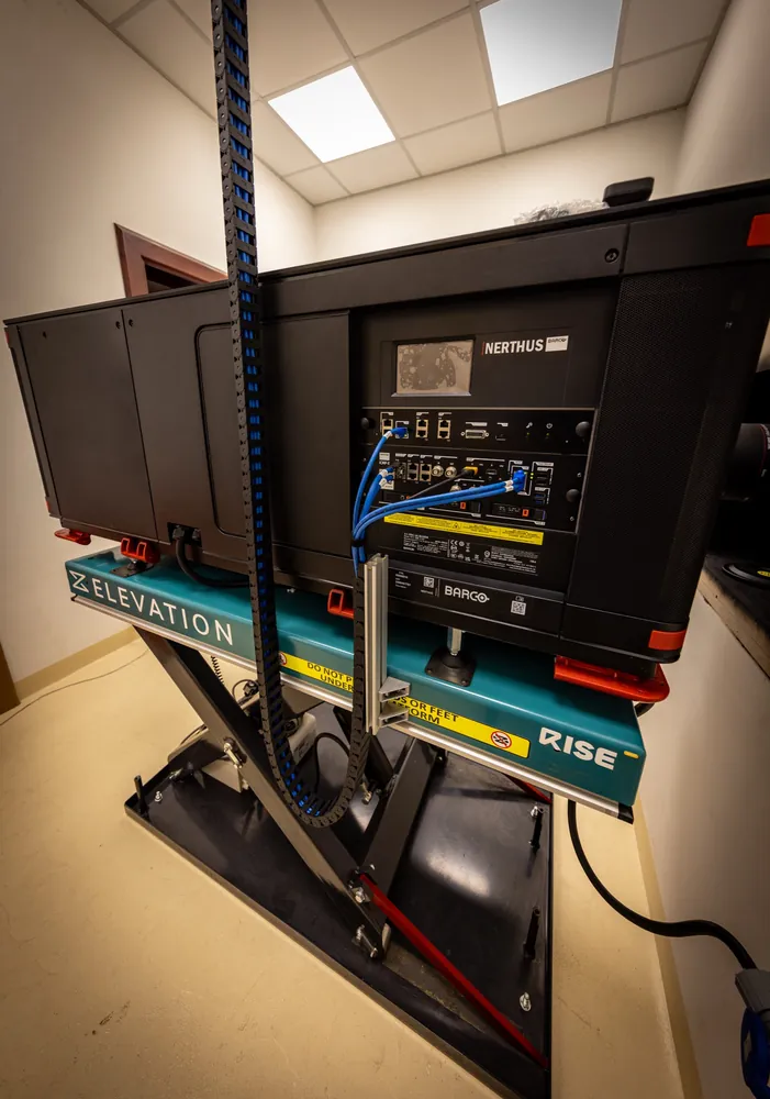 Barco cinema projector mounted on a hydraulic lift platform in the plant room